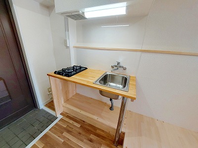 おしゃれで機能的なキッチンは、天板を木で造作し、温かみとデザイン性をプラス。さらに洗濯機置き場や冷蔵庫スペースも同じ木材で一体化させ、他にはない統一感のある仕上がりに。デッドスペースだった場所もハンガーポールと仕切りを設けて収納として活用し、無駄のない洗練された空間を実現。床材には明るいトーンを採用し、ナチュラルで開放感のある居心地のよい住まいとなりました。機能美とデザインが融合した、こだわりの詰まった一室です。