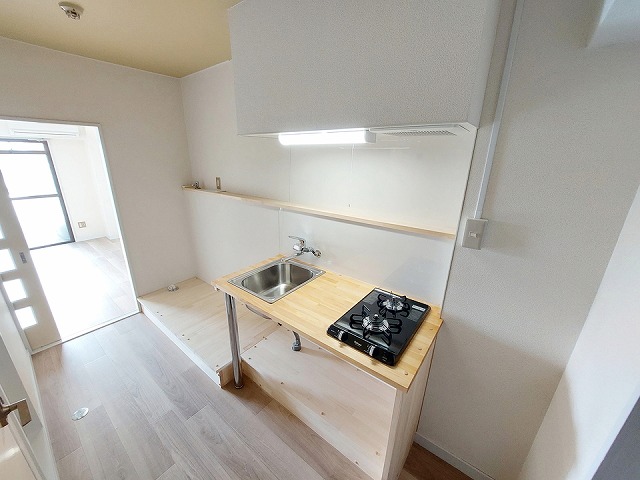 おしゃれで機能的なキッチンは、天板を木で造作し、温かみとデザイン性をプラス。さらに洗濯機置き場や冷蔵庫スペースも同じ木材で一体化させ、他にはない統一感のある仕上がりに。デッドスペースだった場所もハンガーポールと仕切りを設けて収納として活用し、無駄のない洗練された空間を実現。床材には明るいトーンを採用し、ナチュラルで開放感のある居心地のよい住まいとなりました。機能美とデザインが融合した、こだわりの詰まった一室です。