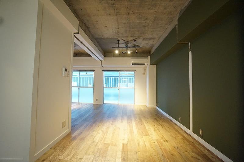 ナチュラルな木目が心地よい床に、無骨さを際立たせるコンクリートむき出しの天井。あえて対比を活かすことで、ラフさと上質さが共存するインダストリアル空間が生まれます。壁には印象的なグリーンアクセントクロスをあしらい、アンティーク調照明が柔らかな光で空間に表情をプラス。素材の質感と色のバランスが、暮らしに程よい緊張感と落ち着きを与える、こだわりのリフォームです。
