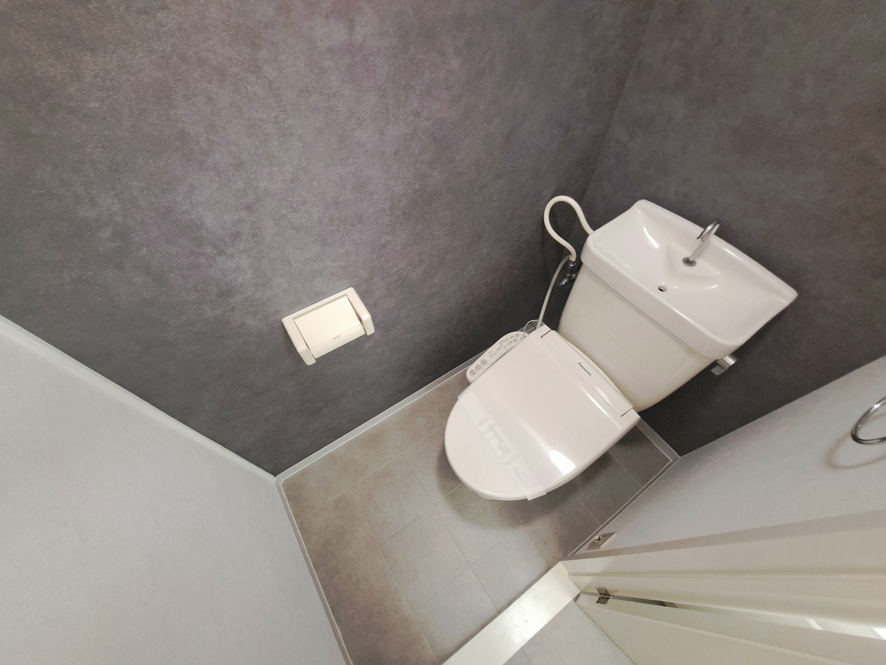 グレーを基調にした清潔感あふれるトイレスペース。リノベーションによって空間全体が美しく整えられ、アクセントに濃いグレーを使用することで洗練されたデザインに仕上がっています。無駄を省いたすっきりとした内装は、毎日使う場所だからこそ嬉しいポイント。落ち着いたカラーリングが視覚的にも心地よく、清掃性や機能性にも優れた快適な空間です。日常の中で、ふとした安らぎを感じられる場所です。